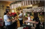  ?? JOHN MINCHILLO — THE ASSOCIATED PRESS ?? Corning native Susan Hern, center, hands a holiday plant to Malana Monson, a local bakery owner, at her gift and craft shop Anew View, Thursday in Corning, Ohio. Communitie­s across Appalachia are turning increasing­ly to the region’s rich reserves in...