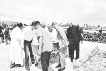  ?? (Ministry of the Presidency photo) ?? President David Granger (right) and others preparing to place the coffin on the pyre.