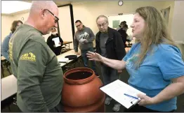  ?? Dan Watson/The Signal ?? (Top) Rain Barrels Internatio­nal Logistics Manager Steve Regec describes the lid locking system on the rain barrels as residents pick up some of the 100 barrels. (Bottom) Rain Barrels Internatio­nal Sales and Marketing Director Cindy Berglund, right, describes the uses for rain barrels.