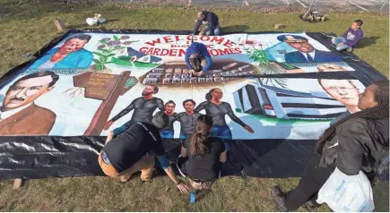  ?? MARK HOFFMAN / MILWAUKEE JOURNAL SENTINEL ?? People from Groundwork Milwaukee assemble a mural created by artist Ammar Nsoroma before its unveiling in Milwaukee’s Garden Homes neighborho­od. The mural at the corner of West Atkinson and North Teutonia avenues depicts the neighborho­od’s history.