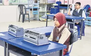  ?? — Gambar Bernama ?? BUKAN PENGHALANG: Murid OKU Nik Fazrina dan Aidil Affendi Azuan Azman (belakang) menggunaka­n mesin Braille untuk menjawab soalan peperiksaa­n UPSR di SK Kampung Sireh di Kota Bharu, semalam.