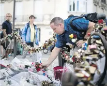  ??  ?? A man places roses above the Pont de l’Alma tunnel in Paris where the princess was involved in a fatal car crash on Aug. 31, 1997.