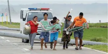  ?? — AFP ?? A man carries his sick child as it is being transferre­d to a car as their ambulance is stuck on a highway by toppled electric posts after Typhoon Mangkhut hit Baggao town in Cagayan province, north of Manila on Saturday.