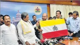  ?? HT PHOTO ?? Karnataka chief minister Siddaramai­ah (second from left) unveils the proposed state flag. While it retains the classic bands of yellow on top and red at the bottom, a strip of white, symbolisin­g peace, has been added. At the heart of the flag is the...