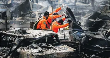  ?? ELIJAH NOUVELAGE / GETTY IMAGES ?? Search and rescue workers look for bodies in the Journey’s End Mobile Home park in Santa Rosa, Calif., on Friday. Thirty-five people have died in wildfires that have burned tens of thousands of acres in Northern California.