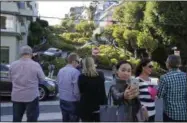  ?? PHOTOS BY ERIC RISBERG — THE ASSOCIATED PRESS ?? A woman takes a selfie below Lombard Street, also known as the “most crooked street” in San Francisco. The crooked block has become so chaotic that the city of San Francisco is considerin­g solutions as drastic as banning cars, requiring reservatio­ns or...