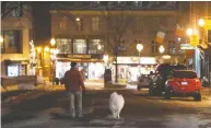  ?? JACQUES BOISSINOT / THE CANADIAN PRESS FILES ?? A lone man walks his dog in the middle of a deserted street in old Quebec City as a curfew begins in the province of Quebec to counter the spread of COVID-19.