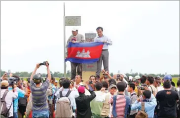  ?? VIREAK MAI ?? CNRP lawmakers hold a Cambodian flag in front of Border Post 203 in Svay Rieng’s Kampong Ro district during a visit to the Cambodia-Vietnam border last year.