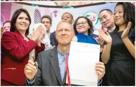  ?? ASHLEE REZIN/ SUN- TIMES ?? LEFT: Gov. Bruce Rauner smiles after signing the TRUST Act on Aug. 28.