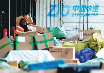  ?? JASON LEE / REUTERS ?? A worker carries parcels at a logistics center of ZTO Express in Beijing.