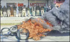  ?? PTI ?? Police personnel look on as tyres are seen ablaze during a strike in protest against the bill, in Dibrugarh on Tuesday.