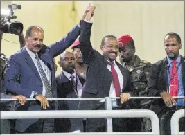  ?? Mulugeta Ayene ?? The Associated Press Eritrean President Isaias Afwerki, second left, and Ethiopia’s Prime Minister Abiy Ahmed, center, hold hands as they wave at the crowds Sunday in Addis Ababa, Ethiopia.