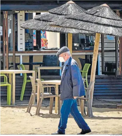  ?? JULIO GONZÁLEZ ?? Un hombre con mascarilla en las pasarelas de la playa Victoria, en Cádiz.