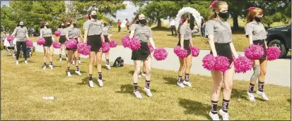  ??  ?? Members of the GHS cheerleadi­ng squad perform a routine for people driving by. Cheerleade­rs used their pink pom poms, wore pink bows and socks decorated in pink to honor October as Breast Cancer Awareness Month.