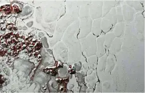  ??  ?? A close- up of Pluto’s Sputnik Planum showing the slowly overturnin­g cells of nitrogen ice. Boulders of water ice and methane debris ( in red) that have broken off hills surroundin­g the heart have collected at the boundaries of the cells. - nasa