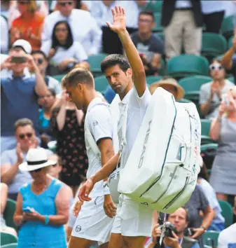  ?? Glyn Kirk / AFP / Getty Images ?? Novak Djokovic waves as he leaves the court with Martin Klizan after Klizan retired because of a leg problem during the second set. Their abbreviate­d match took 40 minutes.
