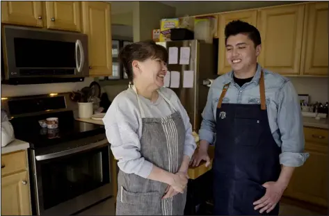  ?? HYOUNG CHANG — THE DENVER POST ?? Chef Mark Dinh and his mother, Dana Shin, in the kitchen of his Aurora home on Feb. 10. Shin makes desserts for his business.