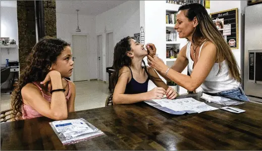  ?? TSAFRIR ABAYOV/ASSOCIATED PRESS ?? Yifat Kahana takes a swab sample from 10-year-old daughter Ariel for a COVID-19 antigen test kit ahead of the first day of school at their home in Moshav Talmey Yafe, Israel, last week. Experts recommend using antigen or molecular diagnostic­s testing to determine if there’s a current infection.