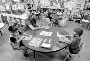  ?? SUSAN STOCKER/SOUTH FLORIDA SUN SENTINEL ?? Sylvie Mizrachi, a David Posnack JCC preschool teacher, helps students Itay Daniyarov, 5, Sabrina Zee, 5, and Nathan Shay, 4, with their Passover art projects on March 11 in Davie.