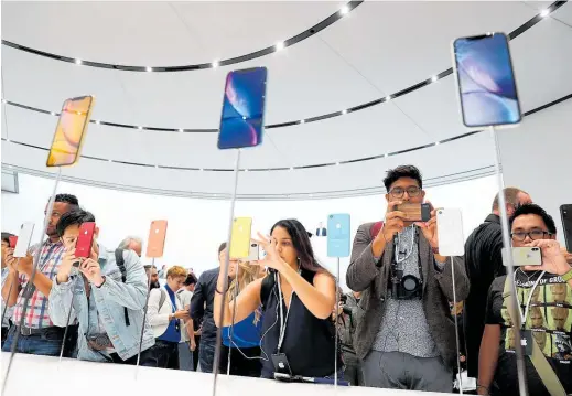  ?? Photo / Getty Images ?? Shoppers check out the new range of iPhones unveiled earlier this month.