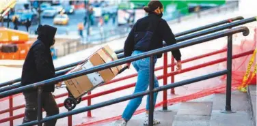  ?? File/agence France-presse ?? Customers carry packages up the stairs to a US Postal Service office in New York.