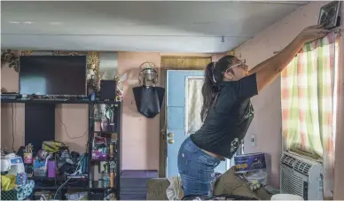  ?? MARK HENLE/THE REPUBLIC ?? Syndi Flores takes a photo off of the wall of her family’s home at the Tempe Mobile Home Park.