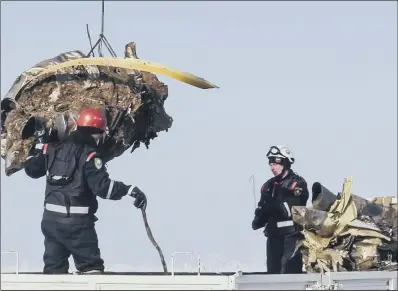  ??  ?? Emergency personnel load debris of an engine from the AN-148 plane crash on to a truck near Domodedovo airport, Moscow.