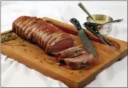  ?? RICHARD DREW — THE ASSOCIATED PRESS ?? Bacon-wrapped beef tenderloin with green peppercorn and thyme sauce