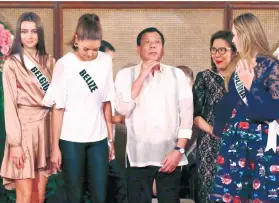  ?? /AP PHOTO/ BULLIT MARQUEZ ?? MISS U. President Rodrigo Duterte jokes about how tall the Miss Universe contestant­s are as he poses with them during their courtesy call at Malacañang Palace.