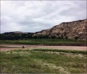  ?? CAREY J. WILLIAMS — THE ASSOCIATED PRESS ?? Drew Redman and Ryan Johnson riding on the riverbed of the Little Missouri River in western North Dakota. The area is experienci­ng a drought this season, making it possible for Redman to ride across the low-flowing river.