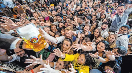  ?? Michael Probst
The Associated Press ?? Young people reach out for free beer in one of the beer tents on the opening day of the 187th Oktoberfes­t beer festival in Munich, Germany, Saturday as Oktoberfes­t is back in Germany after two years of pandemic cancellati­ons.