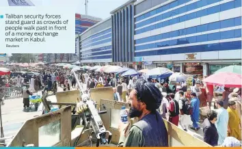  ?? Reuters ?? Taliban security forces stand guard as crowds of people walk past in front of a money exchange market in Kabul.