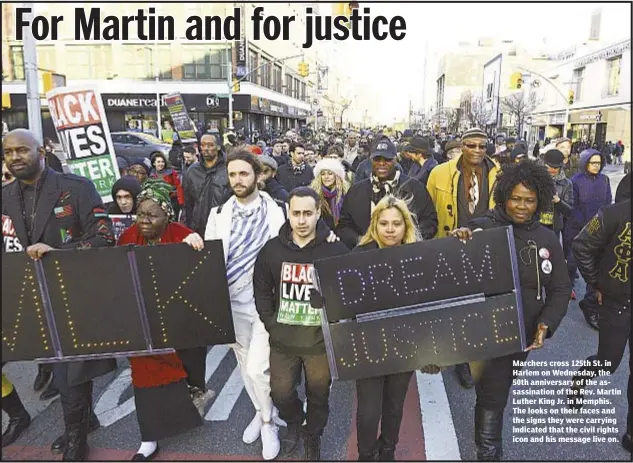  ??  ?? Marchers cross 125th St. in Harlem on Wednesday, the 50th anniversar­y of the assassinat­ion of the Rev. Martin Luther King Jr. in Memphis. The looks on their faces and the signs they were carrying indicated that the civil rights icon and his message...