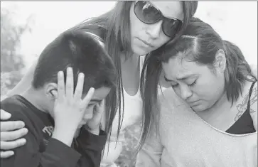  ?? Mark Boster Los Angeles Times ?? FAMILY MEMBERS of the wounded teenager, from left, Andrew Bernal, Araceli Alvarez and Joana Bonilla, weep at a protest Monday. The youth, identified by relatives as Joshua Alvarez, is in critical condition.