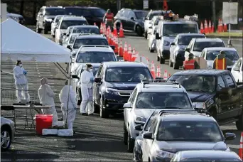  ?? SETH WENIG — THE ASSOCIATED PRESS FILE ?? In this March 24, 2020, file photo, staff at a drive-thru COVID-19 testing site talk to people waiting in line in their cars at the PNC Bank Arts Center in Holmdel, N.J.