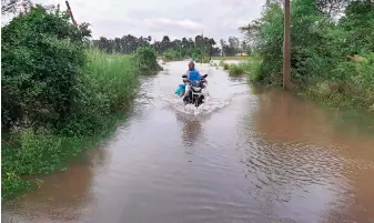  ?? — DECCAN CHRONICLE ?? A motorist tries to negotiate his way across an inundated road after floodwater­s entered villages in Devipatnam mandal of East Godavari district on Thursday.