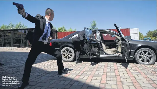  ?? PHOTOS BY AFP ?? Students practise hustling their clients safely into a black Audi with smashed windows.
