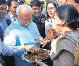  ?? SANJEEV SHARMA/HT ?? CM Manohar Lal Khattar buys a ‘pakoda’ being sold by Congress leaders as CLP leader Kiran Choudhry looks on outside the Haryana assembly in Chandigarh on Tuesday.