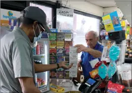  ?? DEAN MUSGROVE — STAFF PHOTOGRAPH­ER ?? A customer purchases lottery scratcher tickets from Joe Chahayed at Joe’s Service Center in Altadena on Tuesday. A $2 billion ticket was purchased there in November.