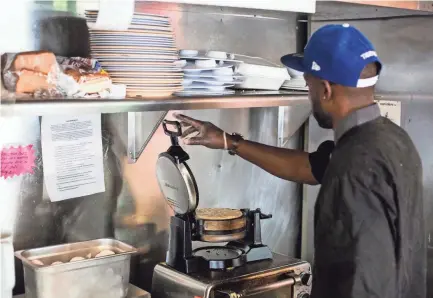  ??  ?? Trashaun Davis cooks up a waffle while working at The Waffle Iron at 4969 Park Ave. on July 1. After a fire at the original location in Colliervil­le, The Waffle Iron has reopened in East Memphis. PHOTOS BY BRAD VEST/THE COMMERCIAL APPEAL