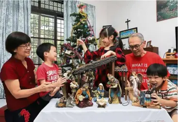  ??  ?? Christmas mood: Choo (left) and her husband Ivan Filmer setting up a nativity set at their home in Sungai Ara, Penang. Joining them are their grandchild­ren (left to right) Luke, Hailey and Adam Chong.