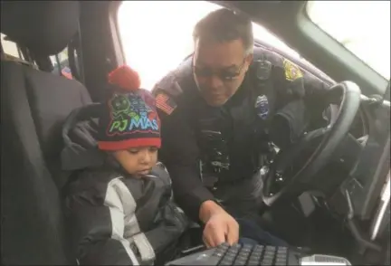  ?? ZACHARY SRNIS — THE MORNING JOURNAL ?? Lorain police Officer Eladio Andujar shows Giovanni Raby, 4, the inside of a squad car Jan. 15.