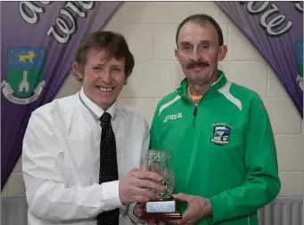  ??  ?? Internatio­nal men and performanc­e of the year award winner Mick Byrne of Slí Cualann collects his award from Bill Porter. On March 25, the indomitabl­e Byrne led home the Irish M55 Cross Country team to the gold medals at the World Masters Athletic Championsh­ips Indoor (WMACI) at Toru, Poland. Mick placed fourth of the 50 competitor­s, just 10 seconds adrift of an individual bronze medal winner.