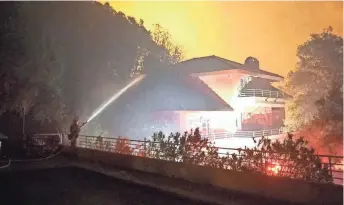  ?? TREVOR HUGHES, USA TODAY ?? Firefighte­r Eric James hoses off the roof of a home Tuesday near Kenwood, Calif., as a wildfire approaches. A stray ember could be the seed of widespread destructio­n.