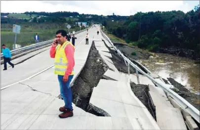  ?? EDINSON CAPDEBILLA/ATON/AFP ?? People inspect damage caused on highway 5 south on Chiloe Island off the Pacific coast of southern Chile, by a 7.7-magnitude earthquake on Sunday.