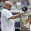  ??  ?? Former New York Yankees pitcher David Wells puts his hat on the 1998 World Series trophy during a ceremony honoring the team prior to a baseball game between the New York Yankees and the Toronto Blue Jays, Saturday.