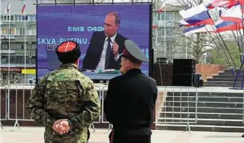  ?? AFP ?? Face the nation Officers watch on an outdoor screen as Russian President Vladimir Putin answers a question during his annual televised phone-in with the nation, in Simferopol, Crimea yesterday.