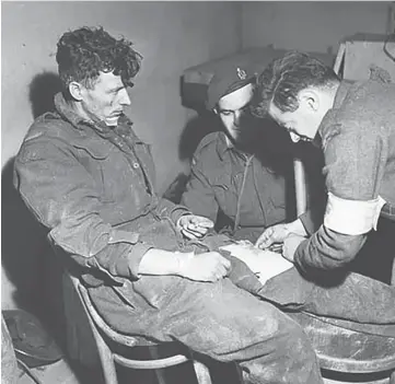  ??  ?? Private W.R. Van Herne of the Calgary Highlander­s receiving an injection in his wounded thigh from Privates G.M. Goderre and H. Couture 1 Nov. 1944 / Beveland Peninsula, Netherland­s. Credit: Ken Bell / Canada. Dept. of National Defence / Library and Archives Canada / PA-131260.