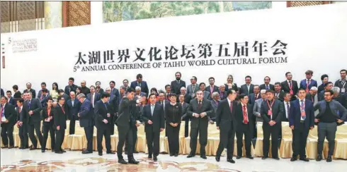  ?? ZOU HONG / CHINA DAILY ?? Taihu World Cultural Forum attendees head for the annual conference’s opening ceremony in Beijing on Thursday after taking a group photo.