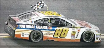  ?? ASSOCIATED PRESS FILE PHOTO ?? Dale Earnhardt Jr. drives in front of fans in the grandstand­s waving the checkered flag after winning the Daytona 500 NASCAR Sprint Cup Series race in 2014.